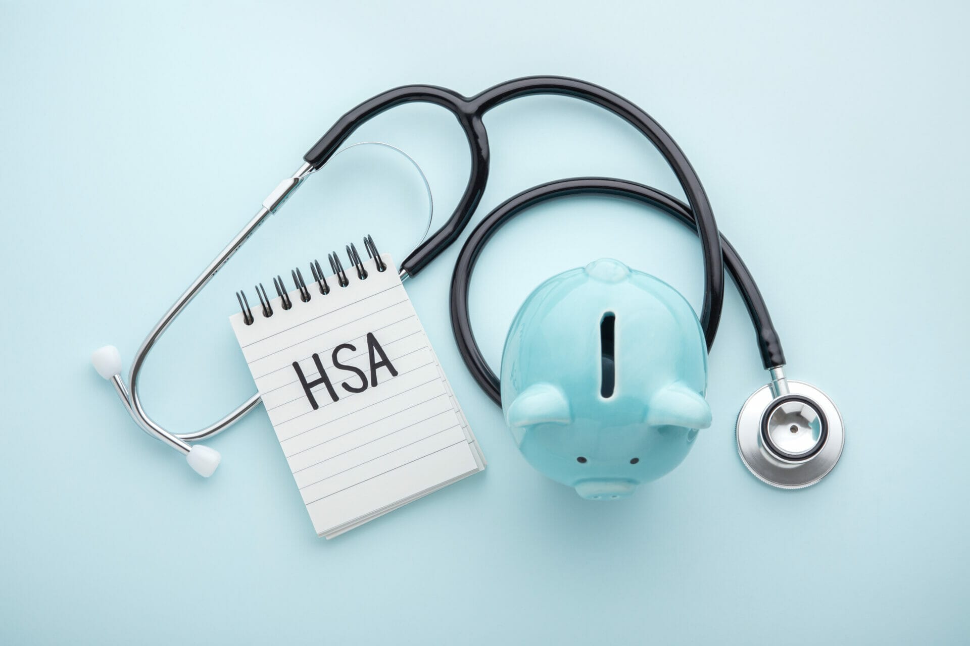 piggy bank, stethescope, and notebook with 'HSA' written on it