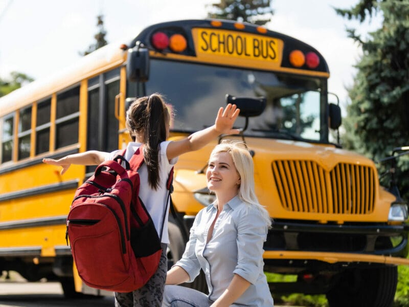 parent saying bye to child at school bus stop