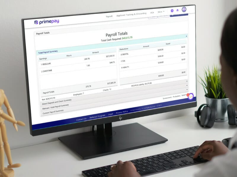 woman out of camera focus looking at computer monitor screen of payroll software