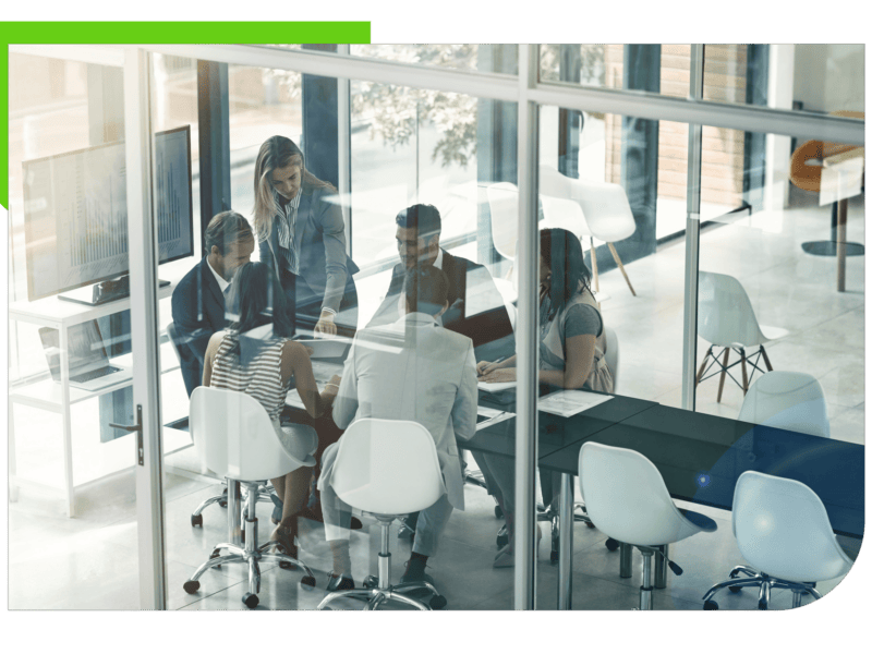 Group of professionals in meeting behind glass doors.