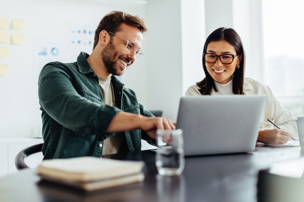 Two business people using a laptop together in an office.