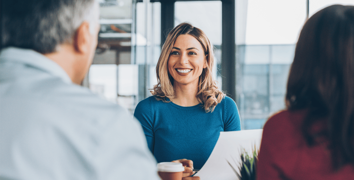 Woman holding paper sitting across two people at desk