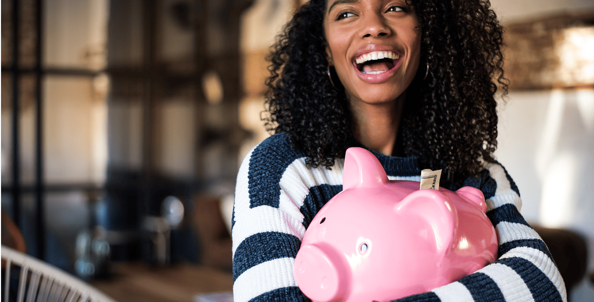 Woman holding a pink piggy bank smiling laughing